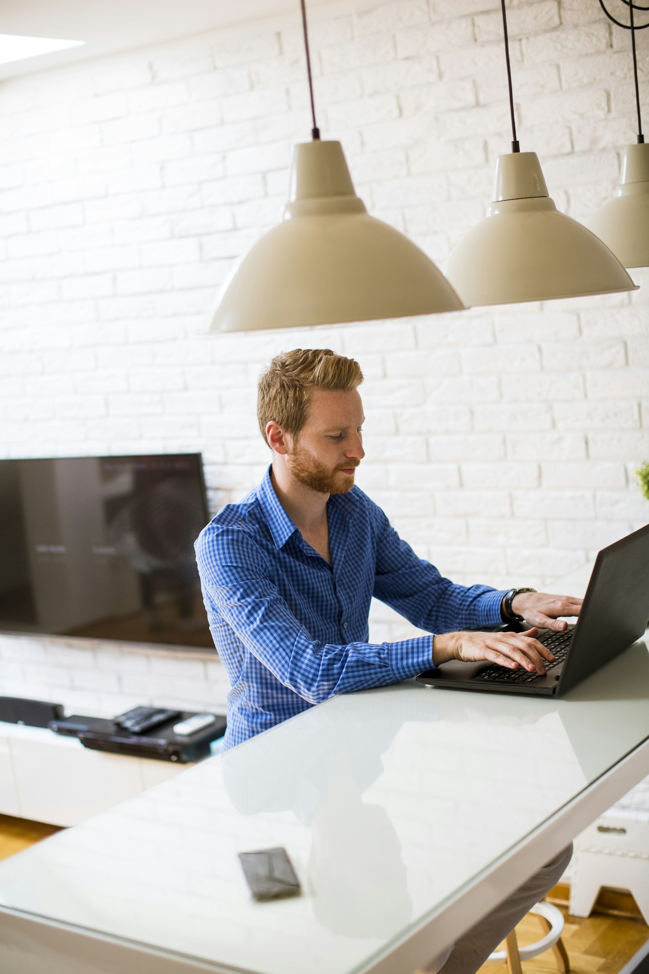 Young man sitting on kitchen desk at home and using laptop